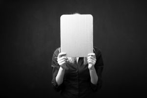 Woman holding empty cardboard in front of her face for facial masking