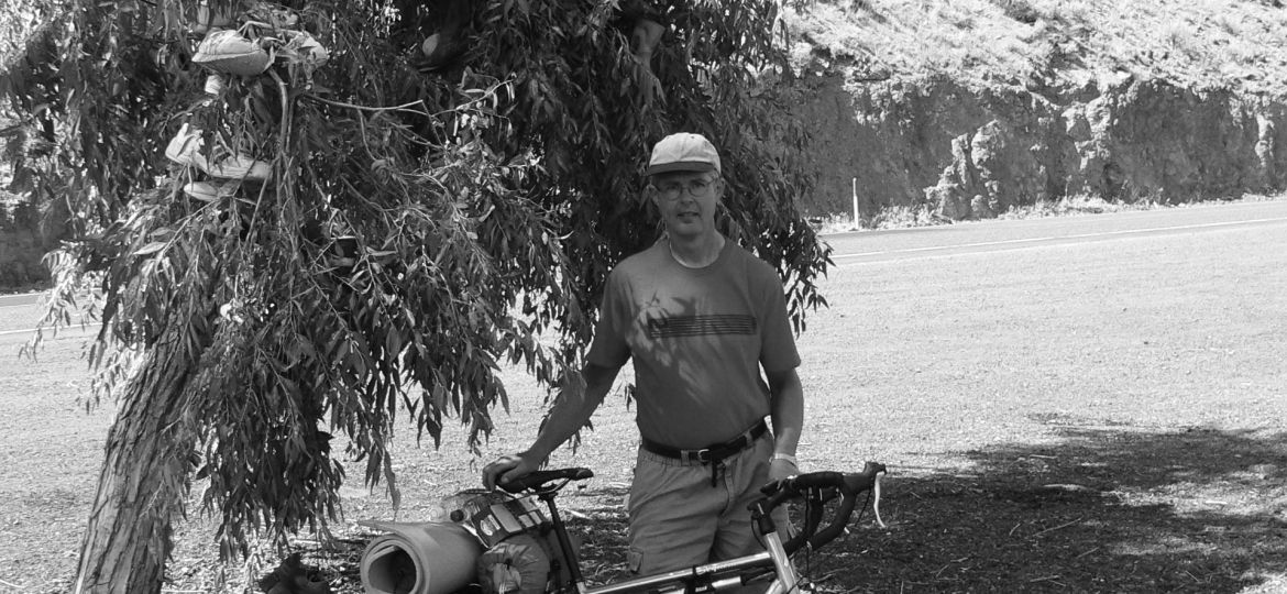 Mature Man with bike by tree