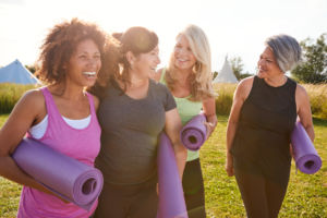 Four women with yoga mats walk to yoga class
