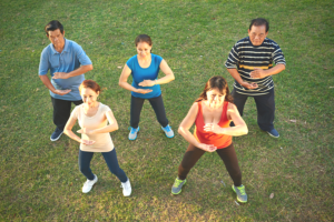 Five adults practicing Tai Chi in park