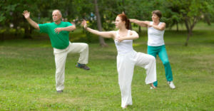 Three people practicing Tai Chi outdoors