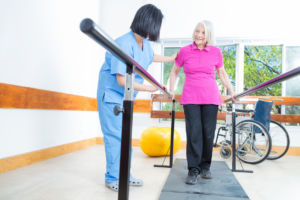 A female physical therapist helps a female patient with walking exercises