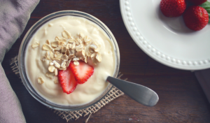 Bowl of yogurt next to plate of strawberries