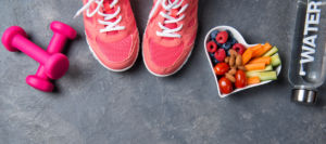 pink sneakers, dumbbells, bottle of water and heart shaped plate with vegetables and berries