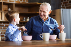 Cheerful little boy and grandfather having a healthy breakfast while sitting in the kitchen