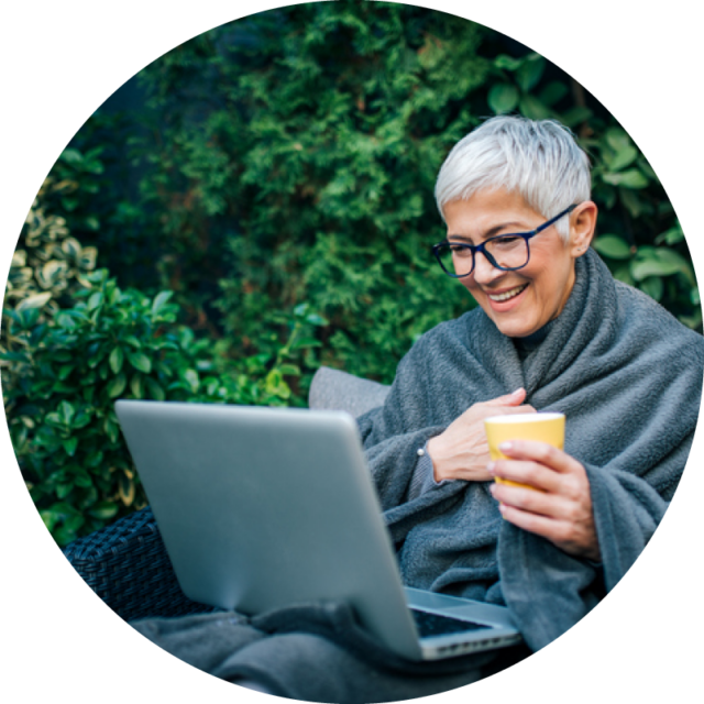 woman sitting outside on computer holding coffee