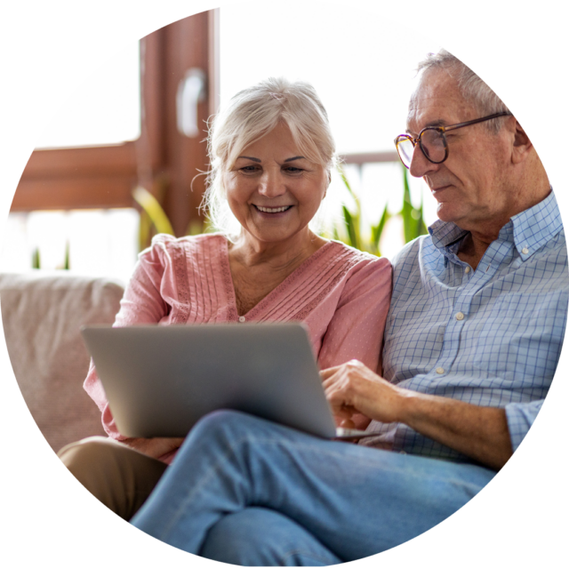 older couple sitting on couch with computer
