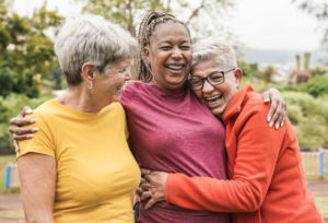 Group of three female friends laughing and hugging outdoors