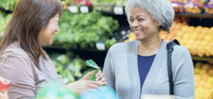 Two women talking in produce section of grocery store