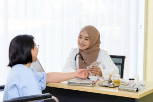 Young asian woman muslim doctor explaining pills to patient in the hospital office
