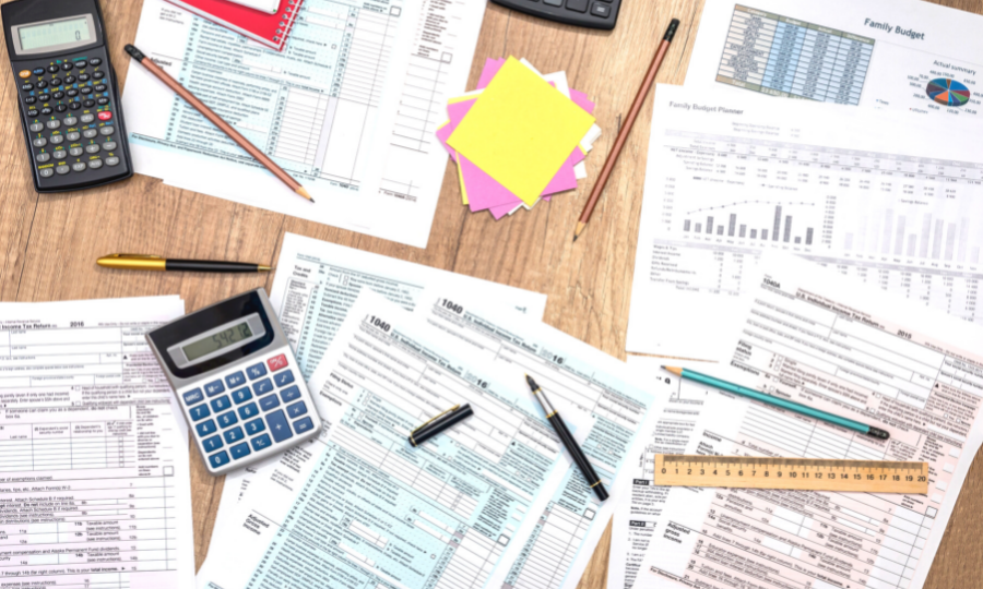 Calculators, pencils, ruler, and tax documents on table