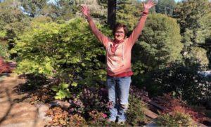 Helen Power outdoors raising arms in victory