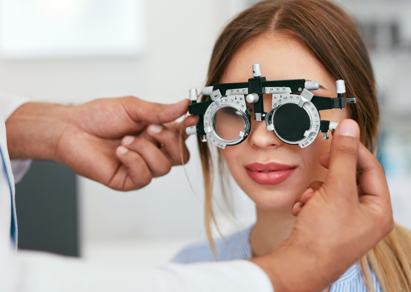 Young woman getting eye exam looking through optical tools