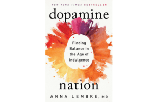 A warm array of watercolors is arranged in a circle around the words "Finding Balance in the Age of Indulgence". The book is titled "dopamine nation" in lowercase font, with the words NEW YORK TIMES BESTSELLER above and ANNA LEMBKE, MD.