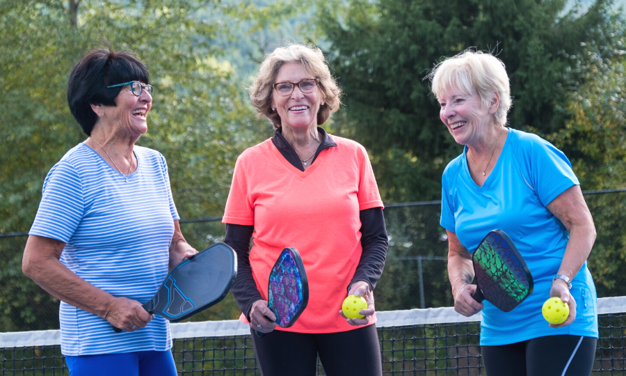Three women smiling and playing pickleball