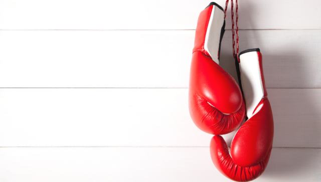 Red boxing gloves hanging from hook on wall