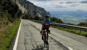 Woman riding a bike through the mountains on a paved road.