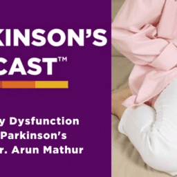 Parkinson's podcast logo. urinary dysfunction A white woman on a couch with white pants, a white shirt, and a pink button-down that is unbuttoned. She is clutching her bladder.