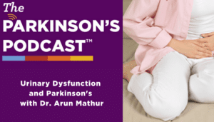 Parkinson's podcast logo. urinary dysfunction A white woman on a couch with white pants, a white shirt, and a pink button-down that is unbuttoned. She is clutching her bladder.