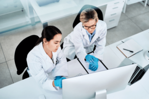 Two female clinicians in a lab studying results on a computer