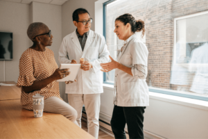 Two physicians talk to woman holding registration form